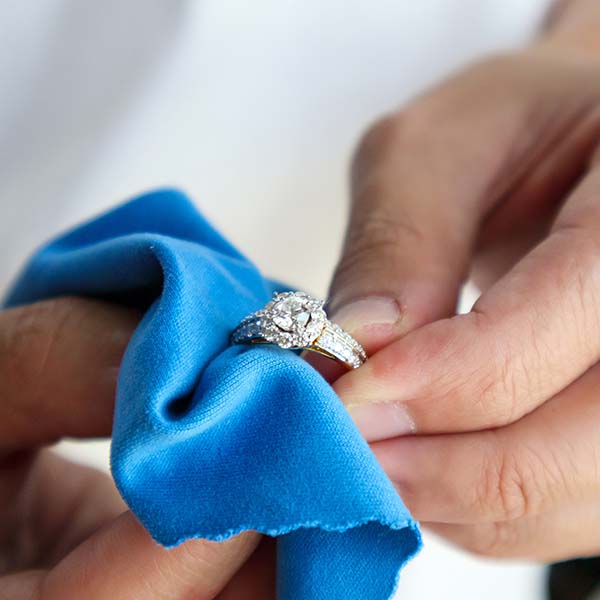 Jeweler cleaning jewelry diamond ring with micro fiber fabric
